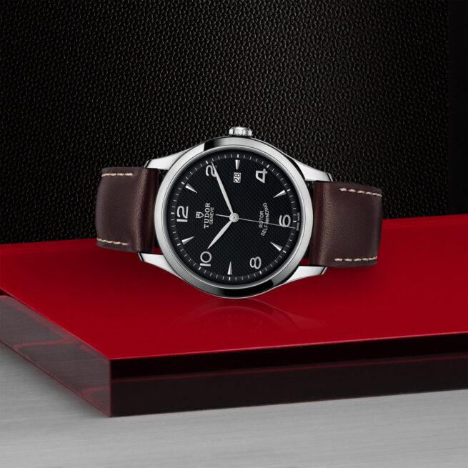 A M91650-0008 watch sitting on a red surface.