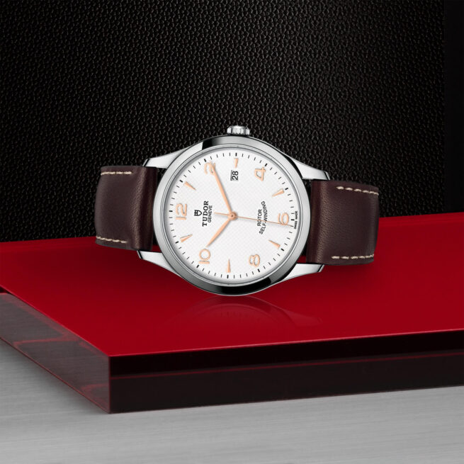 A M91650-0012 watch sitting on a red surface.