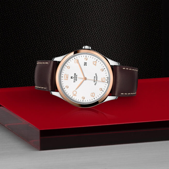 A white and brown M91651-0012 watch on a red surface.