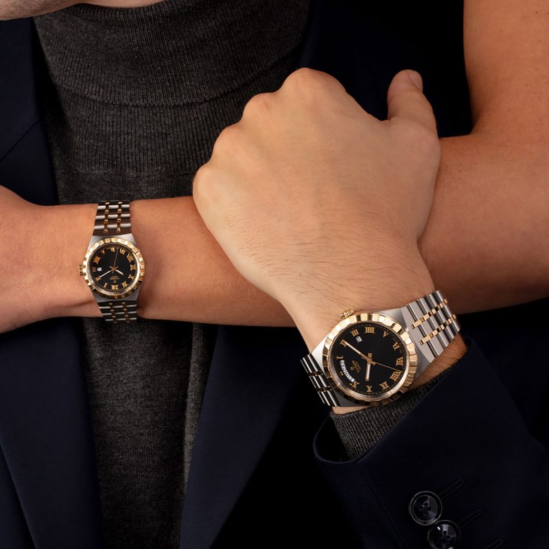 Close-up of two wrists wearing M28303-0003 watches, one in a tuxedo jacket and the other in a dark gray turtleneck.