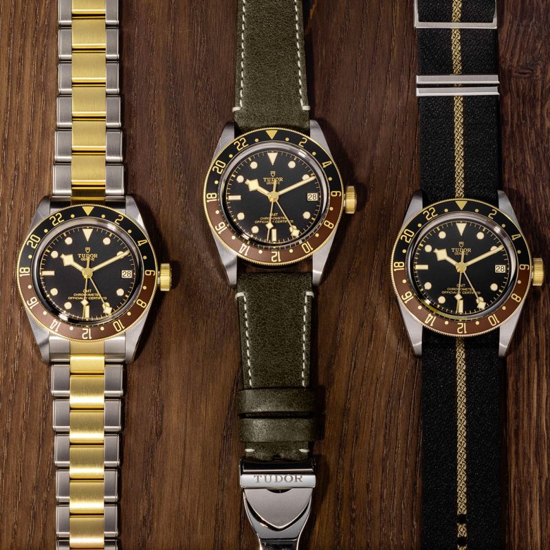Three M79833MN-0004 watches on a wooden table.
