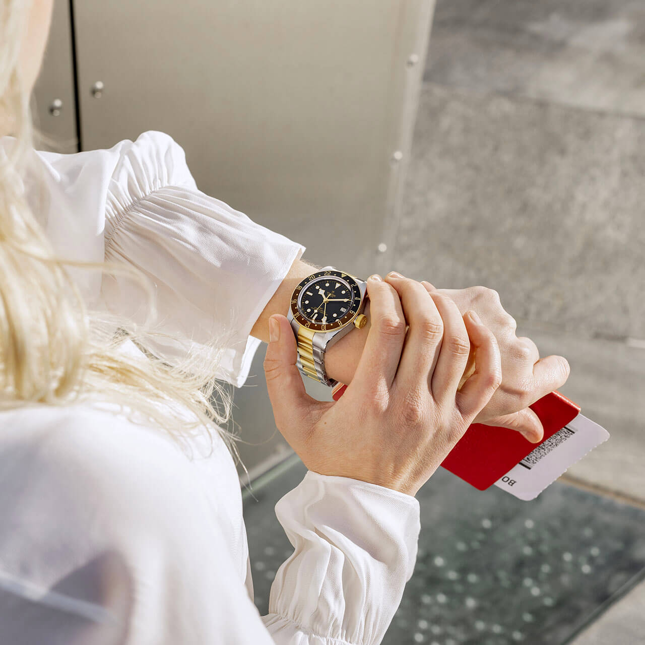 A woman wearing a white shirt with an M79833MN-0004 on her wrist.