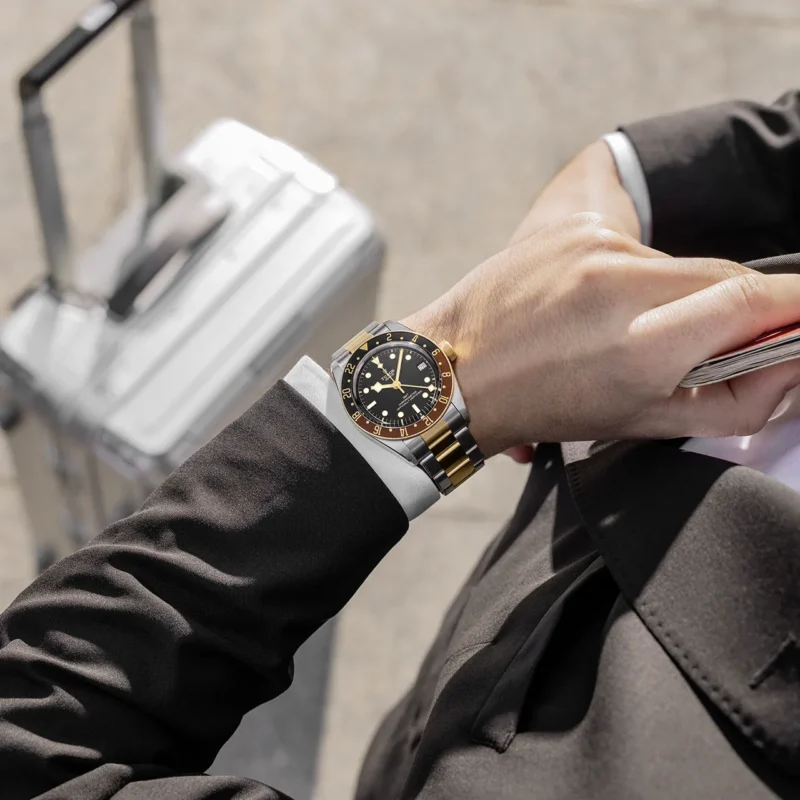 A man in a suit with a M79833MN-0001 on his wrist.