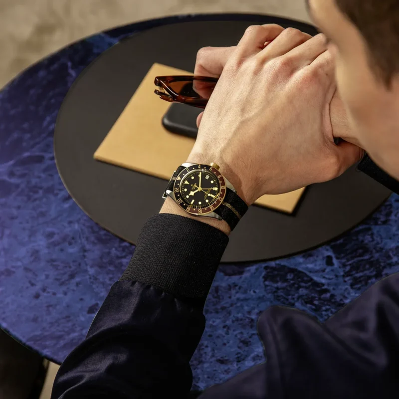 A man sitting at a table with a M79833MN-0004 on his wrist.