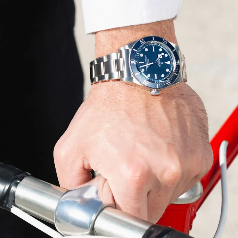 A man is holding a blue M79030B-0001 watch on a bicycle.