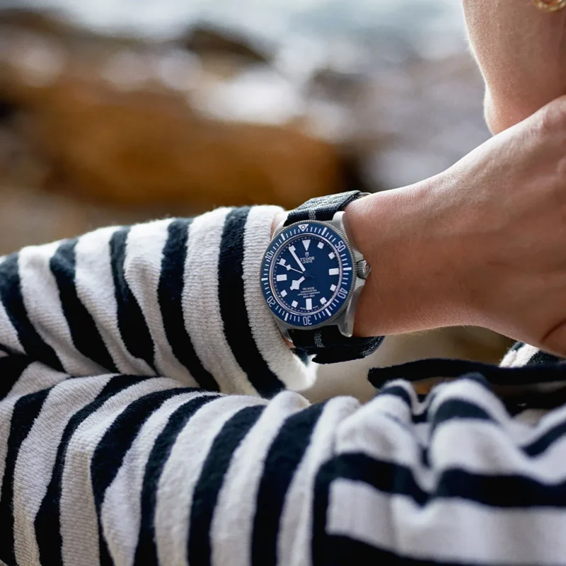 A woman wearing a striped shirt and a M25707B-0001 watch.