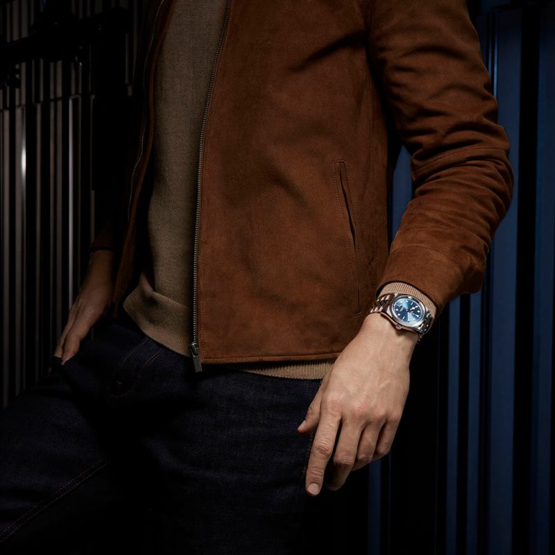 A man wearing a brown jacket and a watch.