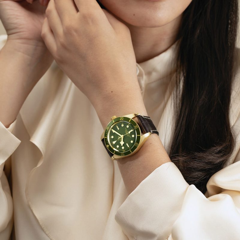 A woman in a white shirt wearing a green watch.
