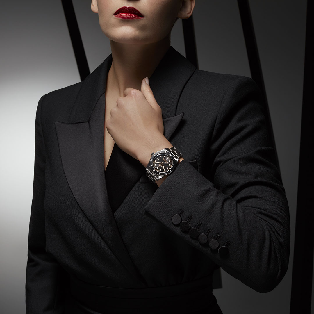 A woman in a black suit wearing a watch.