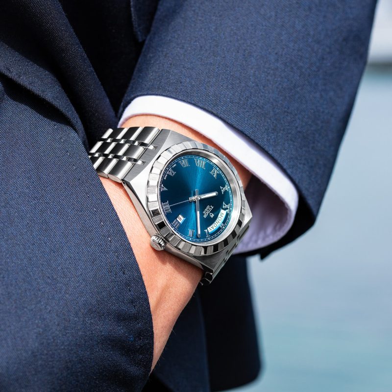 A man in a suit is wearing a blue watch.
