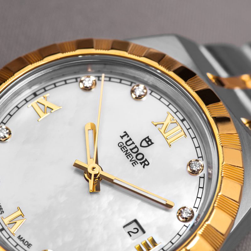A gold and silver watch with a mother of pearl dial.