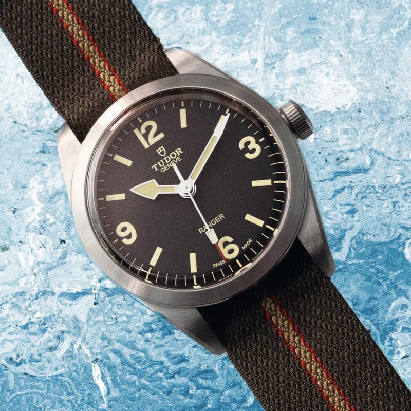 A watch with a black strap sitting on top of ice.