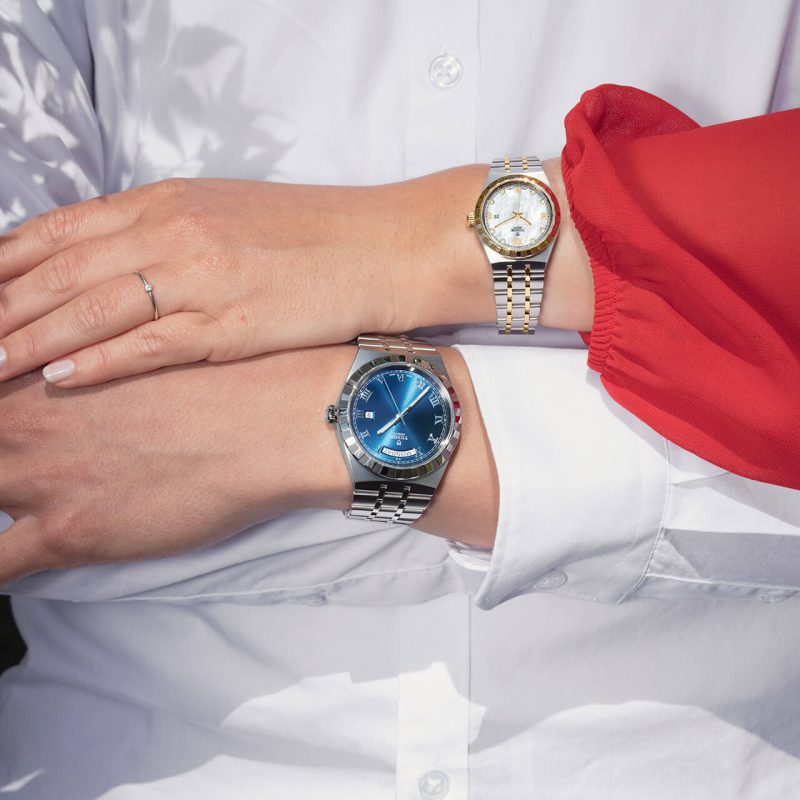 A man and woman wearing watches in front of a white background.