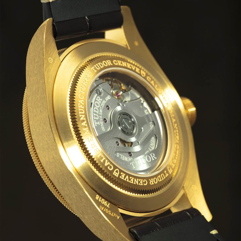 A close up of a gold watch on a black background.