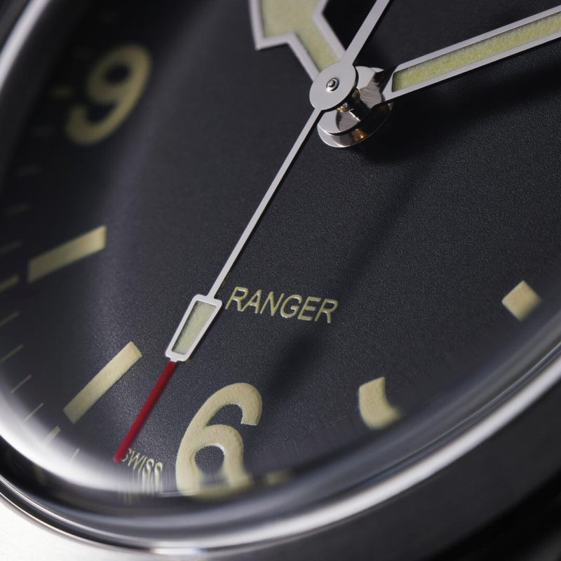 A close up of a black watch with yellow hands.