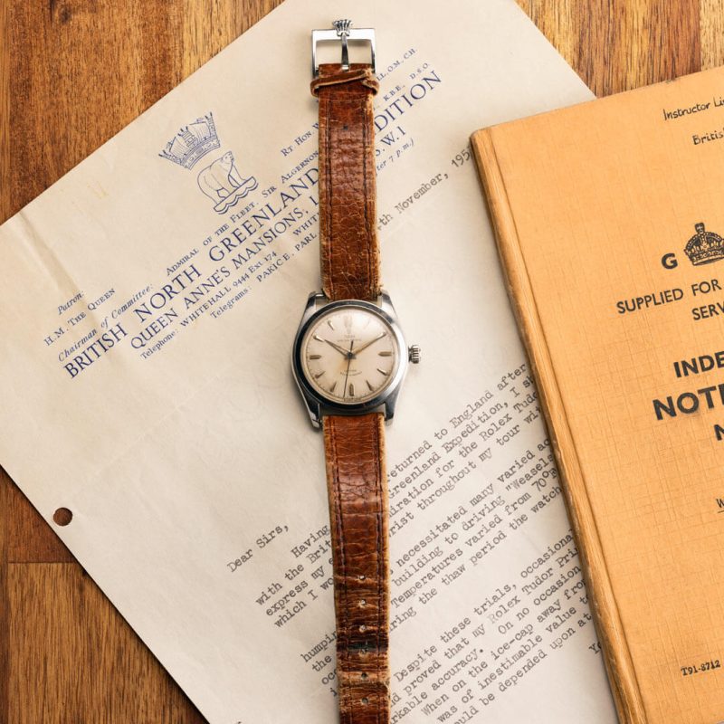 A brown leather watch sits on top of a book.