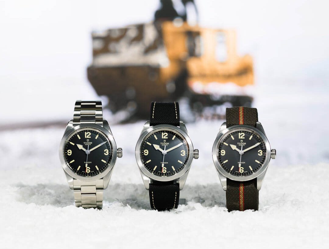 Three watches in the snow with a train in the background.
