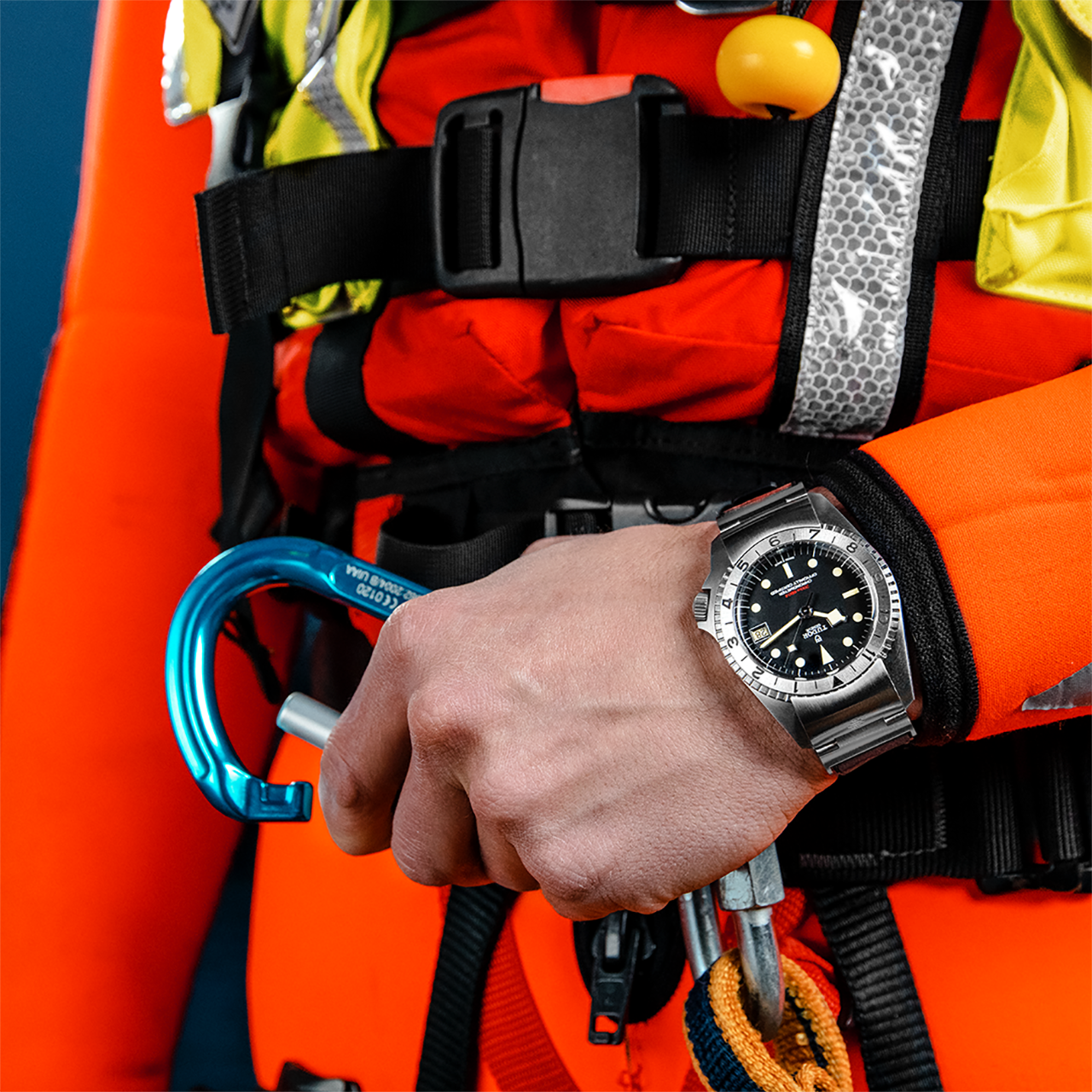 A person in a diving suit holding a watch.