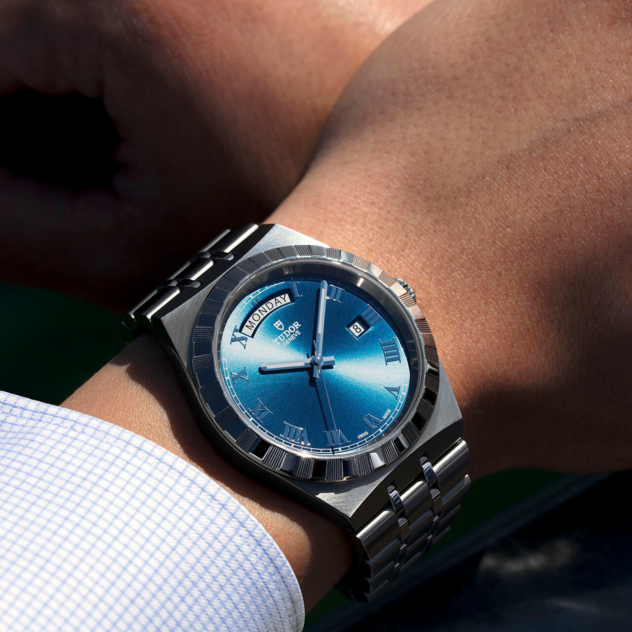 A man's wrist with a blue watch on it.