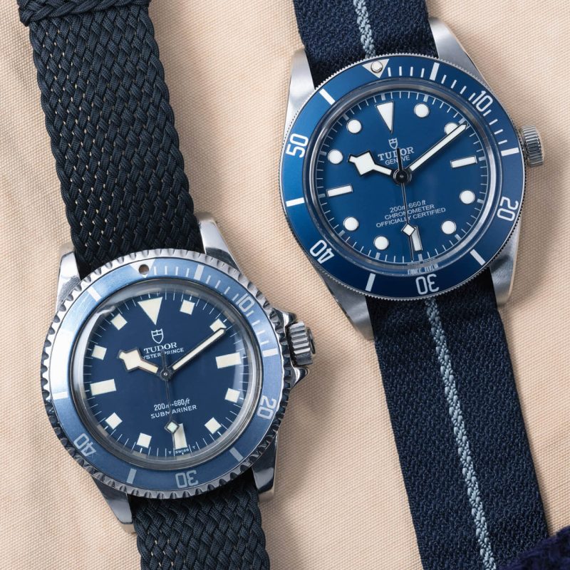 Two tudor watches with blue dials and black straps.