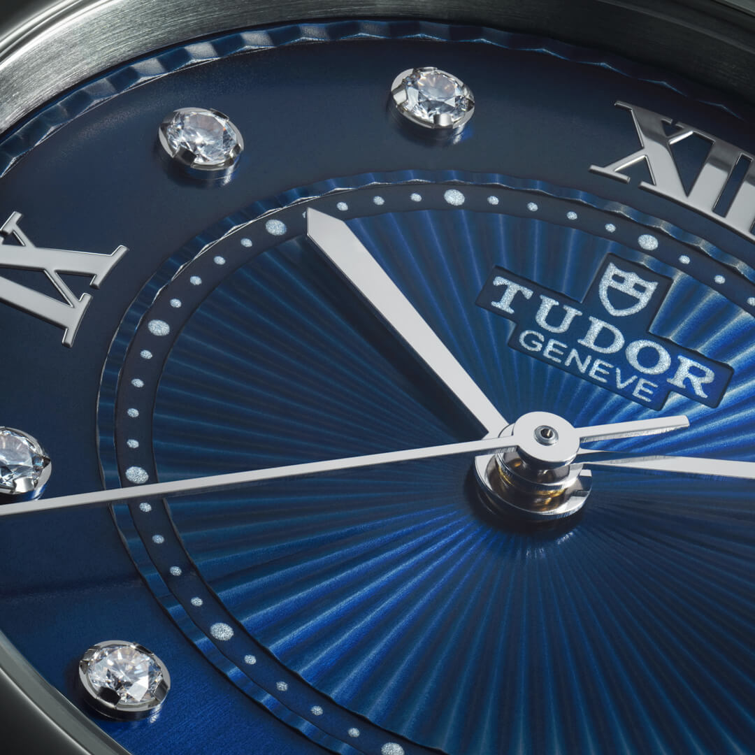 Close-up view of a M35800-0010 wristwatch with a blue dial, silver Roman numerals, and diamond hour markers.