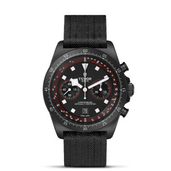 A black wristwatch with three sub-dials, a date display at 6 o'clock, and a black fabric strap. The watch is branded M25827KN-0001 and features a tachymeter scale on the bezel.