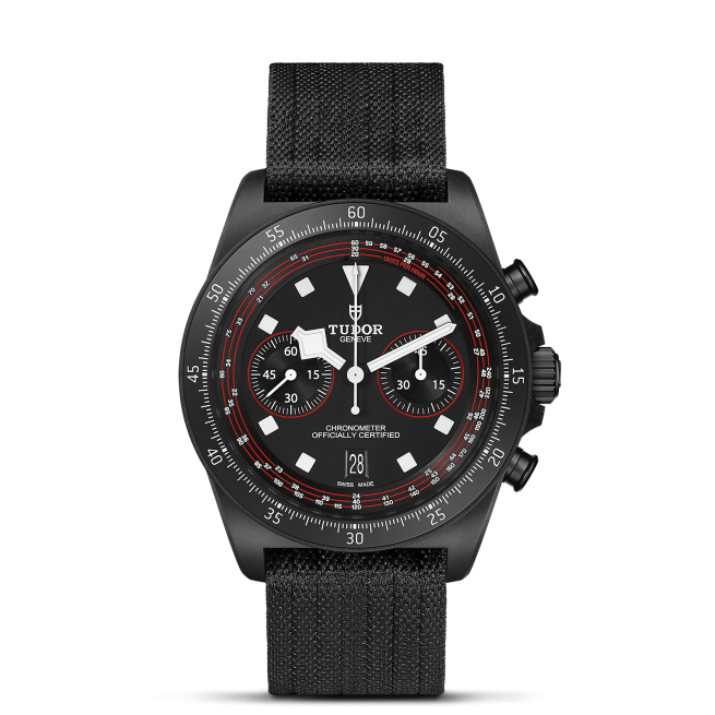 A black wristwatch with three sub-dials, a date display at 6 o'clock, and a black fabric strap. The watch is branded M25827KN-0001 and features a tachymeter scale on the bezel.