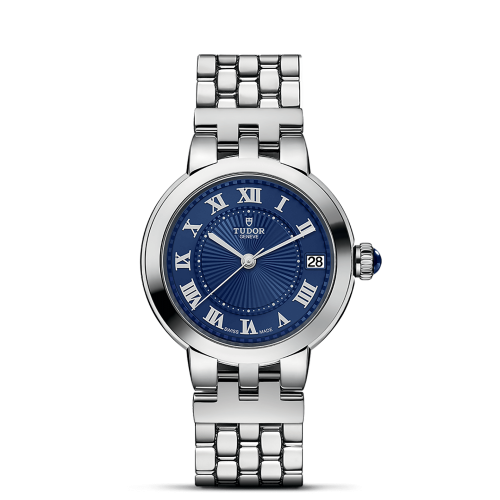 A silver wristwatch with a blue dial featuring Roman numerals and a date display, labeled "Tudor" below the 12 o'clock mark, against a black background.