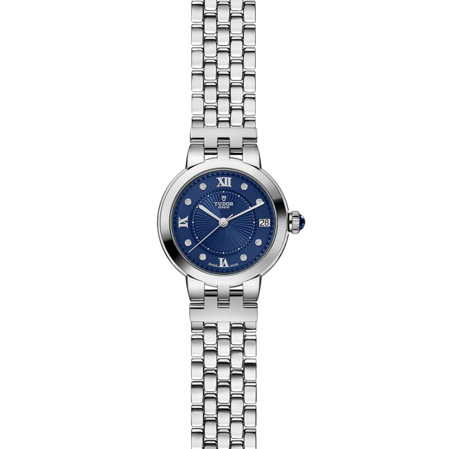 A silver wristwatch with a blue dial, Roman numerals, diamond hour markers, and a date display at the 3 o'clock position. The bracelet has a link design.