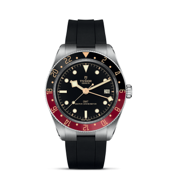 A M7939G1A0NRU-0002 with a black rubber strap, black dial, and a red and black bezel, displaying the date at the 3 o'clock position. The brand name "Tudor" is visible on the dial.