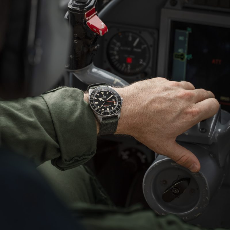 A person wearing a Tudor Pelagos FXD GMT operates a control lever in a cockpit.