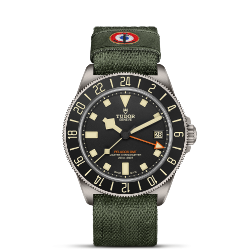 The Tudor Pelagos FXD GMT watch features a black dial with off-white hour markers, and is complemented by an olive green textile strap.