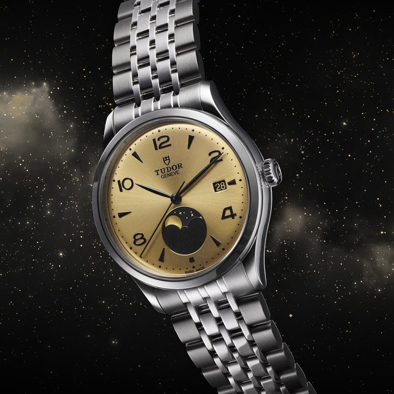 The Tudor Genève M91560-0001 wristwatch features a gold dial, silver metal bracelet, date window, and moonphase display, beautifully showcased against a starry space background.