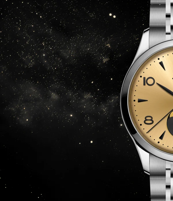 A gold TUDOR wristwatch with a moonphase display and metal bracelet is shown against a background of stars and galaxies.