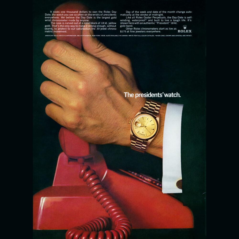 A close-up of a person's wrist wearing a Rolex watch, resting on a red rotary phone, with an advertisement text stating "The president's watch.