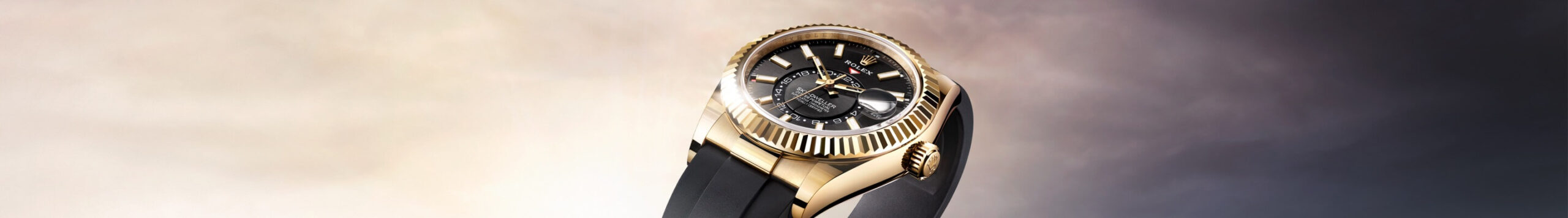 An elegant gold and black wristwatch with a detailed dial, displayed against a soft, gradient sky background.