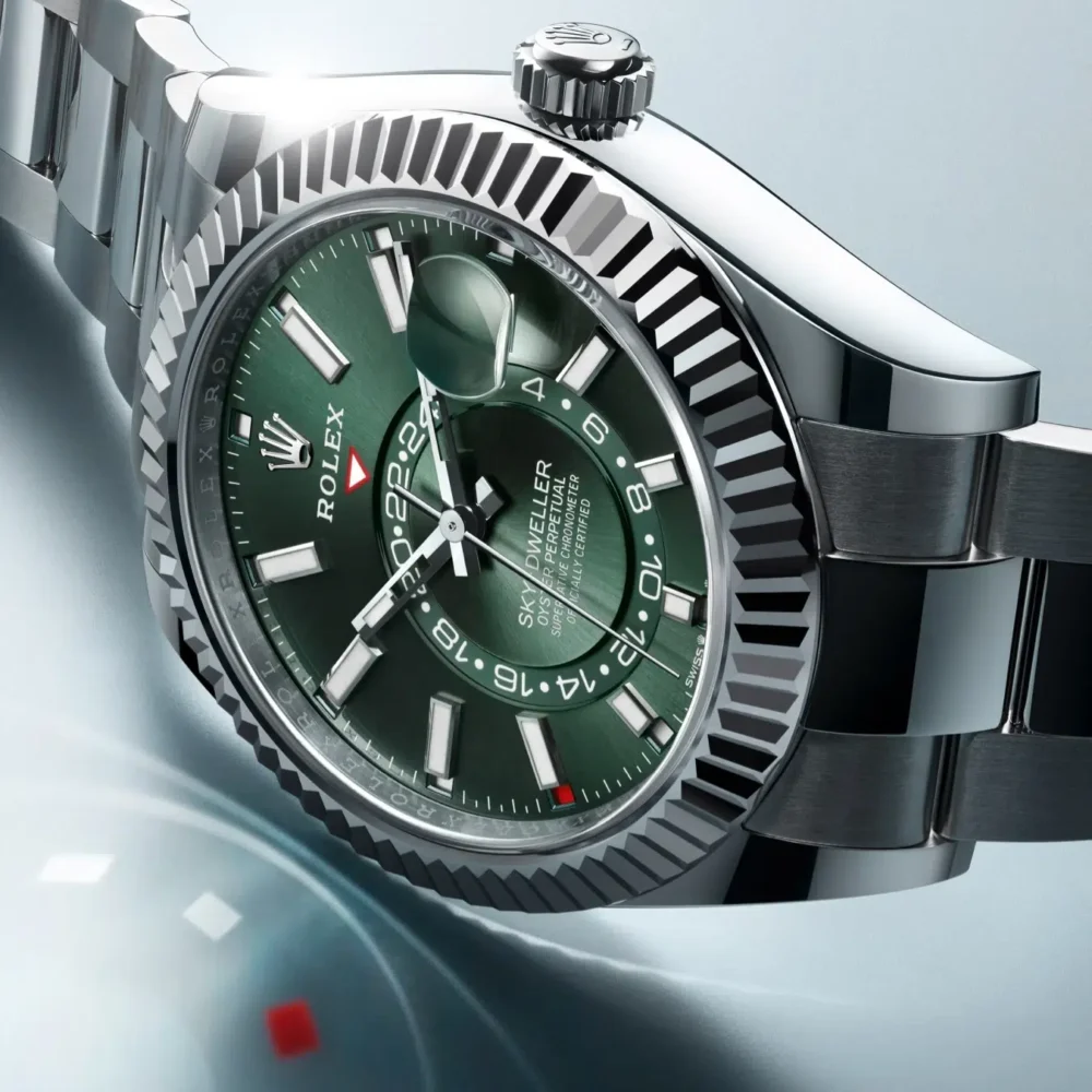 A close-up of a Rolex Oyster Perpetual Submariner watch with a green dial and a stainless steel bracelet.