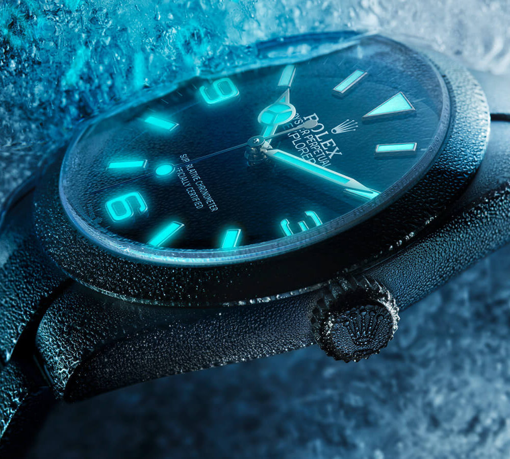 Close-up of a luminescent wristwatch with a black strap against an icy blue background.