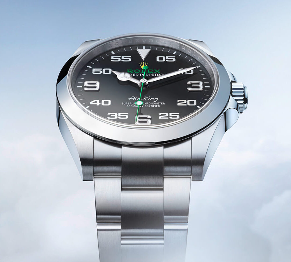An elegant silver wristwatch with black dial, marked numerals, and a date function, set against a cloudy background.