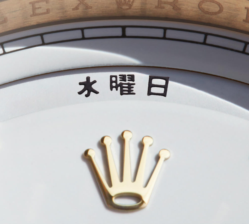 Close-up of a Rolex watch dial displaying the brand name, a date window showing Chinese characters, and a gold crown logo.