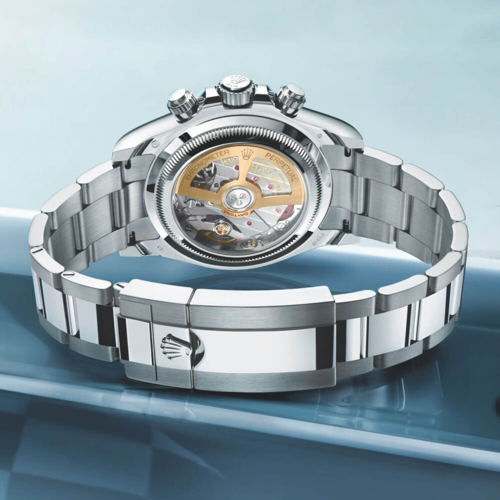 A luxury wristwatch with a transparent back showcasing its mechanical movement, set against a blue background.