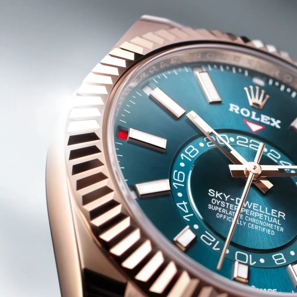 Close-up of a Rolex Sky-Dweller watch with a blue dial and rose gold bezel, highlighting the date window and GMT markings.