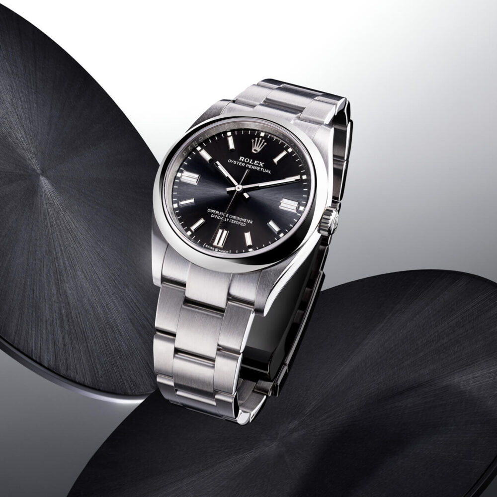 A stainless steel Rolex watch with a black dial and luminescent markers on a partly obscured reflective surface.