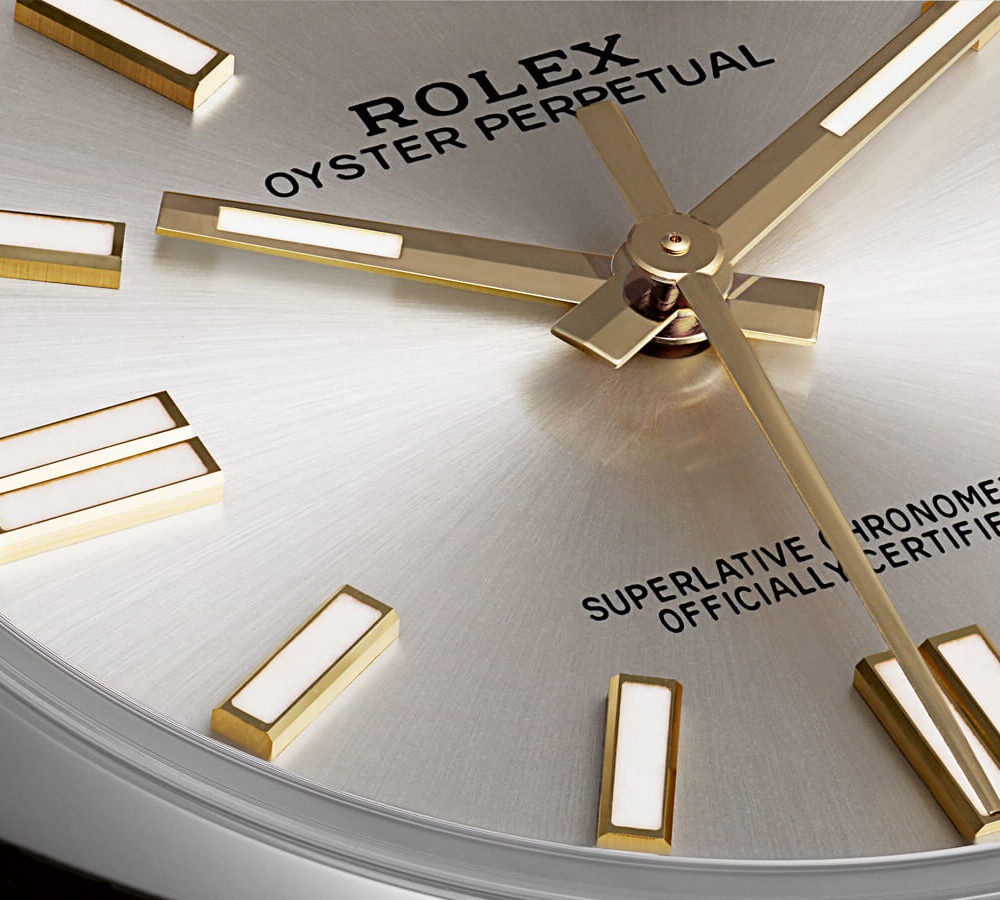 Close-up of a Rolex Oyster Perpetual watch face showing gold hands and markers with branding text.