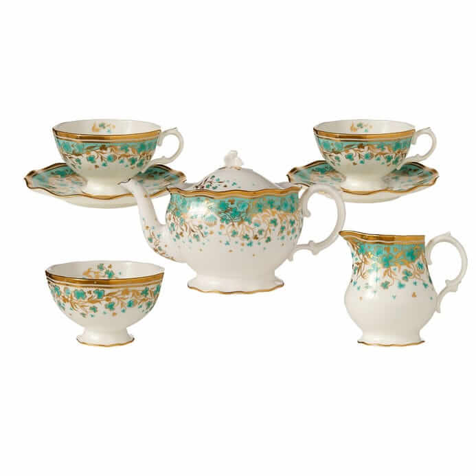 Vintage porcelain tea set with floral pattern, including teapot, cups, saucers, and a creamer, isolated on a white background.