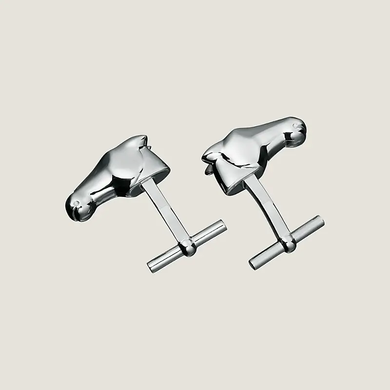 Two silver cufflinks designed to resemble abstract horses, displayed against a plain beige background.
