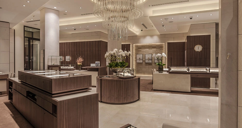 Elegant jewelry store interior with glass display cases, wood paneling, and a large chandelier.