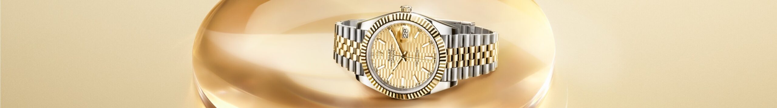 Luxury wristwatch with a gold band and embellished face displayed against a soft golden background.