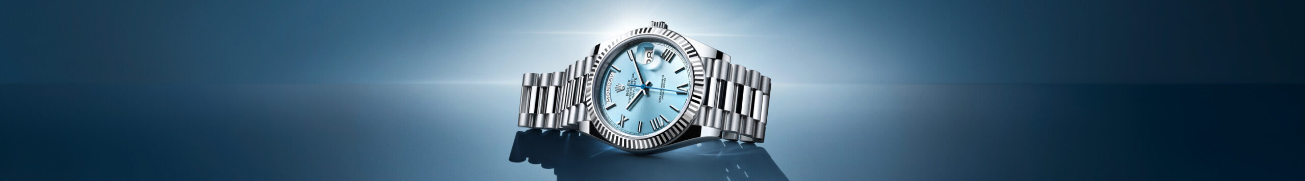 Luxury wristwatch with a metallic band and detailed face, highlighted by a focused beam of light on a reflective blue surface.