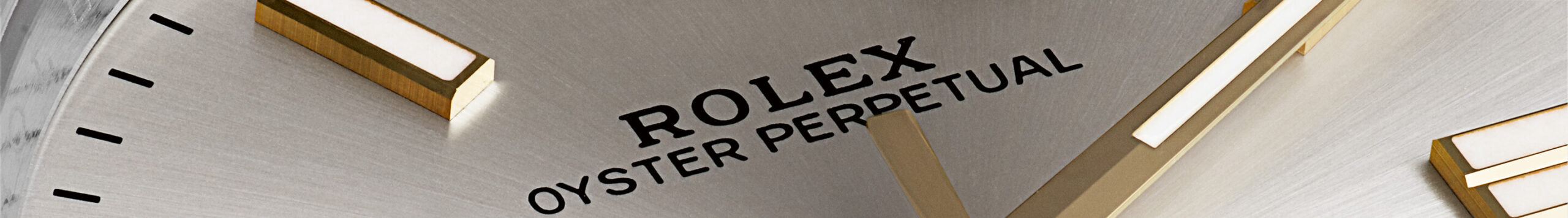 Close-up of a Rolex Oyster Perpetual watch face showing the brand name and gold hour markers.
